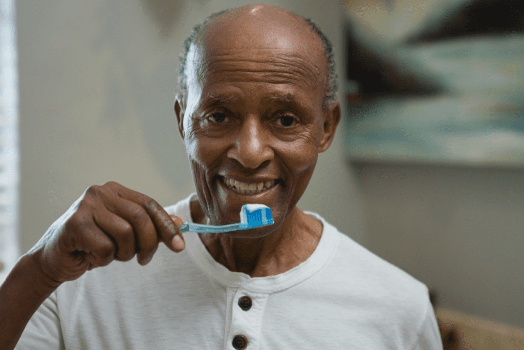 Idoso sorrindo com escova dental a mostra
