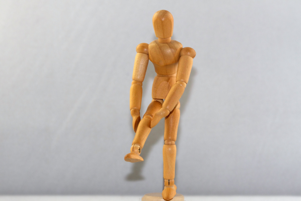 Boneco de madeira mostrando joelho.